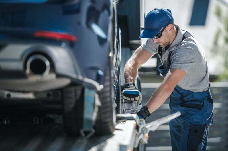 towing-company-worker-securing-vehicle-on-the-truck-platform